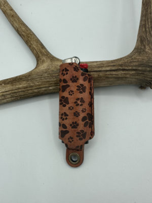 Paw prints laser-engraved onto a leather case for lighters.